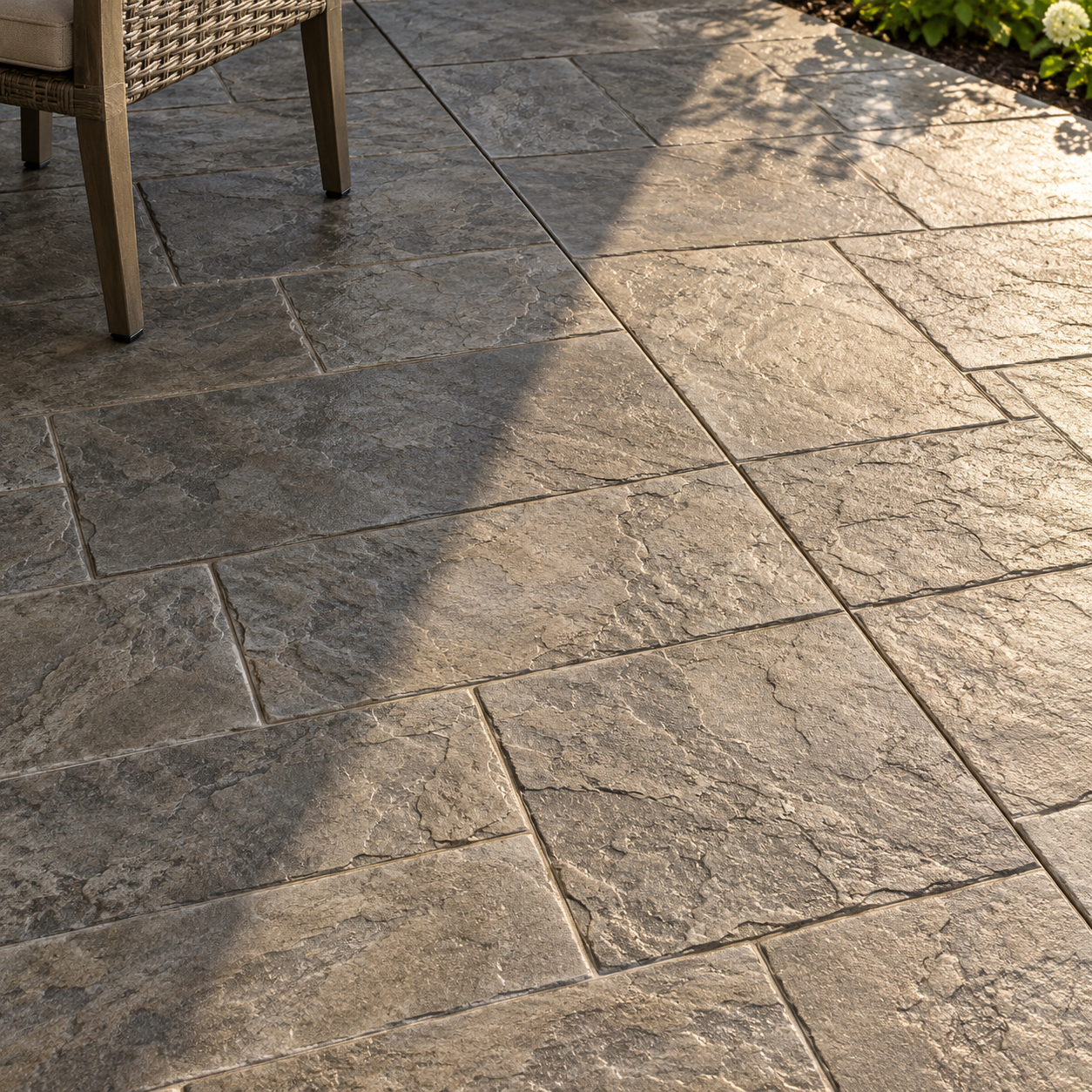 Slate-pattern stamped concrete extends from shade into sunlight beneath an outdoor chair.