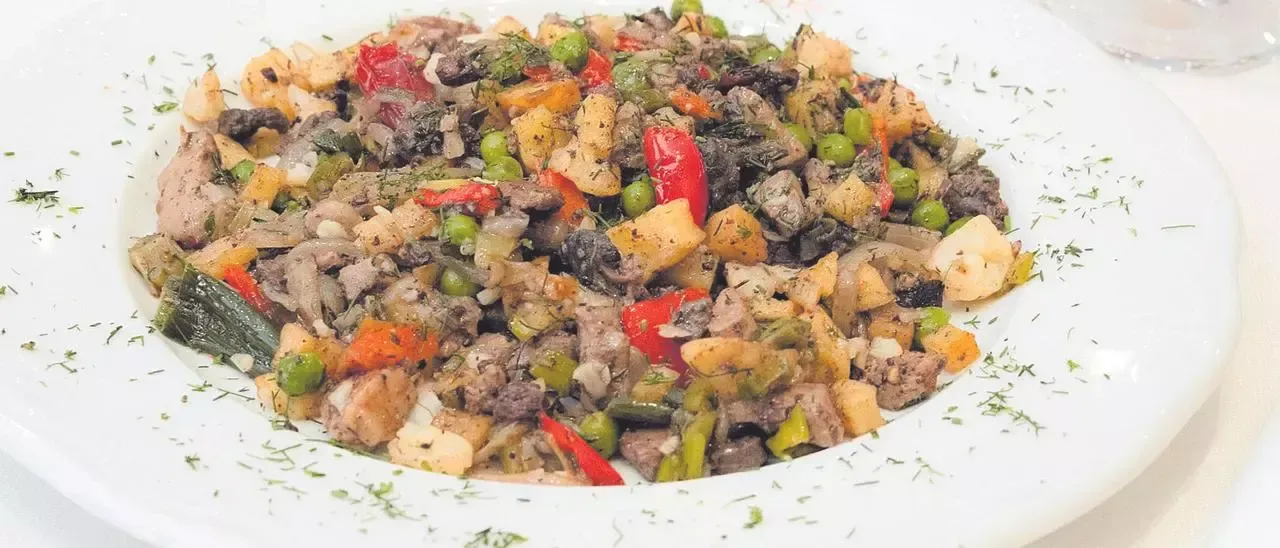 Un plato blanco cubierto con una ensalada de carne y verduras.