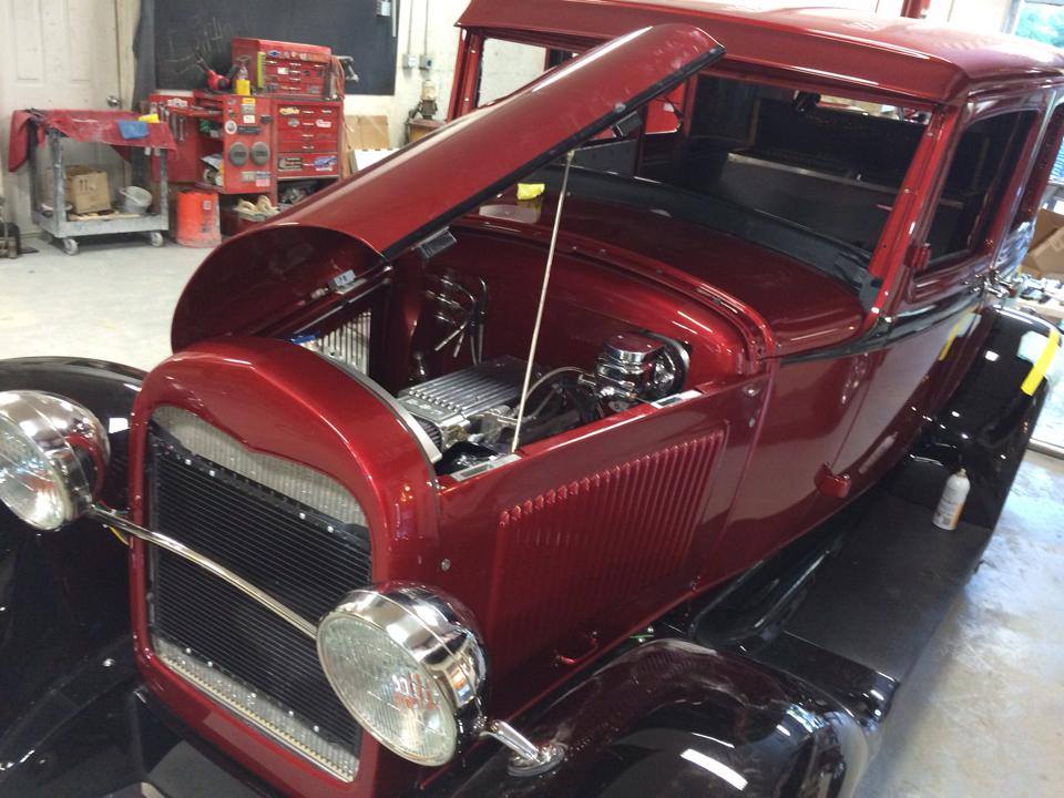 Maroon vintage hot rod with hood open in a garage workshop