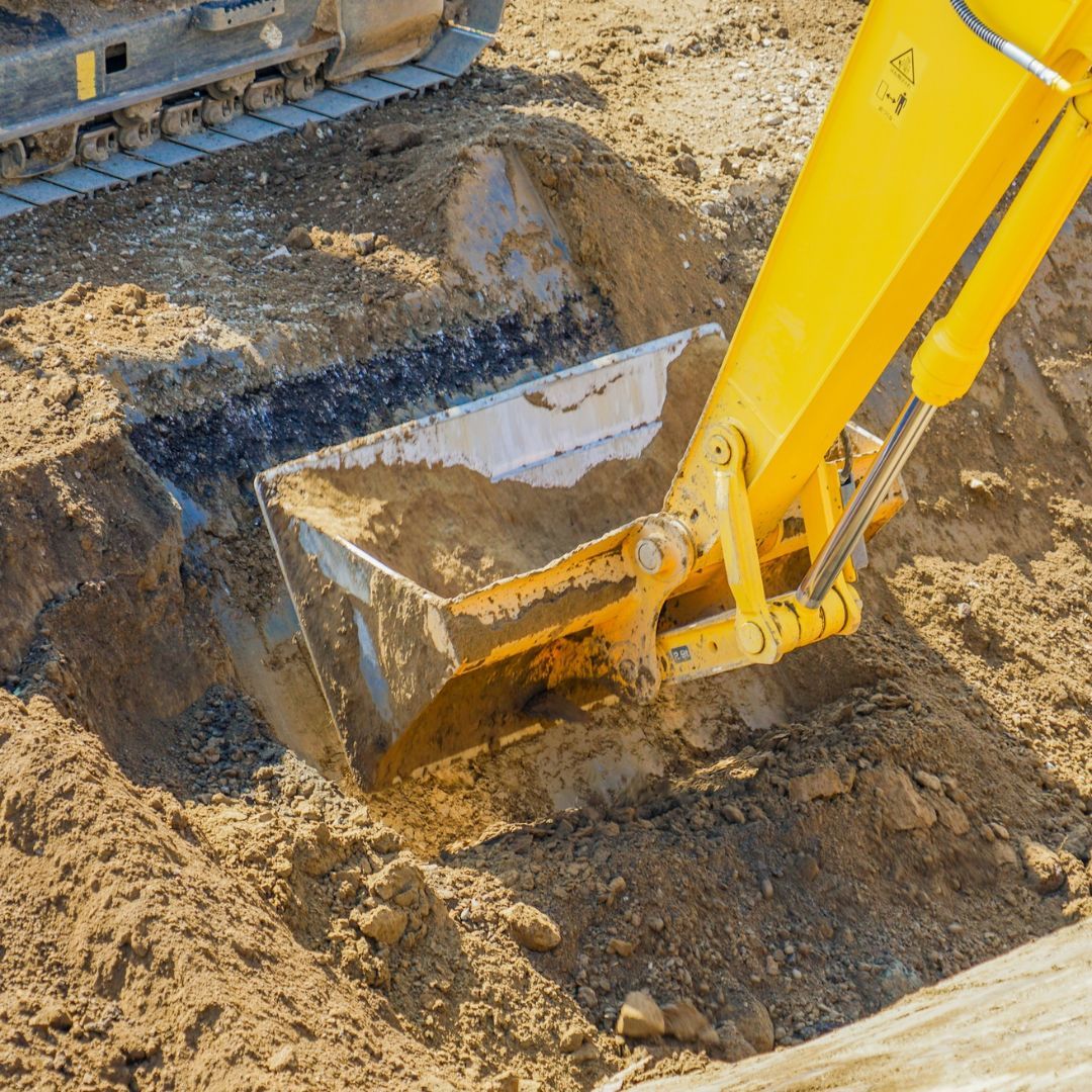 Yellow excavator digging in brown earth.