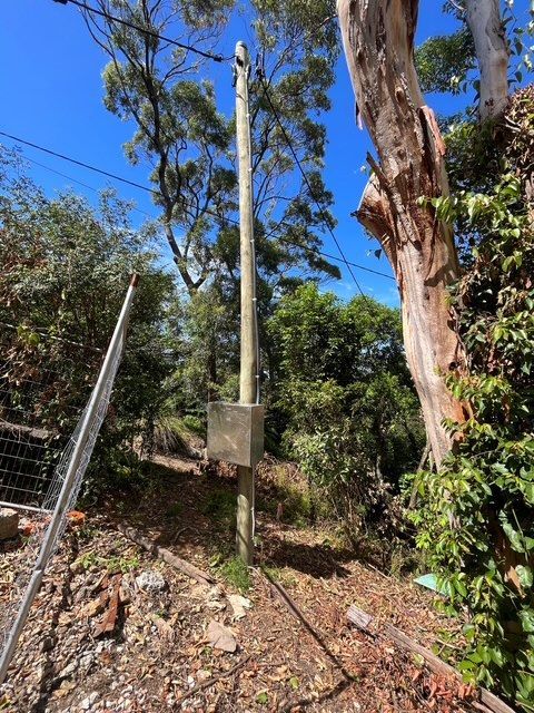 Utility pole and box in a wooded area beside a fence, with blue sky and dry ground. — SRB Electrical Contracting Pty Ltd In Davistown, NSW