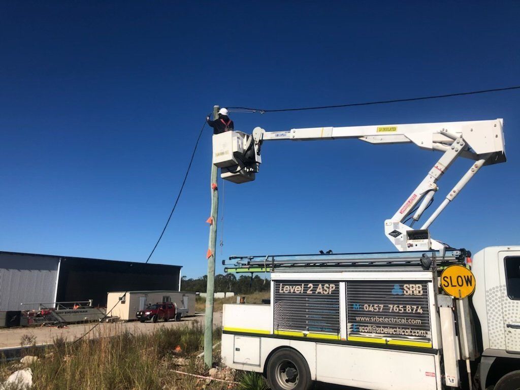 Utility Truck With Bucket Lift and Worker Near a Building — SRB Electrical Contracting Pty Ltd In Central Coast, NSW