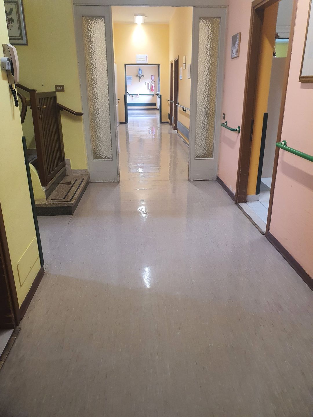 Una persona con i guanti gialli pulisce una bottiglia blu con un panno bianco in un ambiente interno.