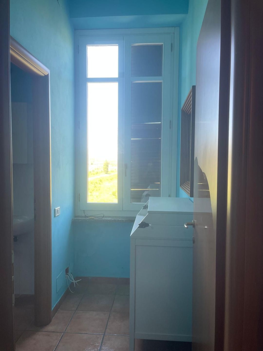 Persona che pulisce un tappeto con l'aspirapolvere, primo piano di una bocchetta scura su un tappeto chiaro in un ambiente interno.