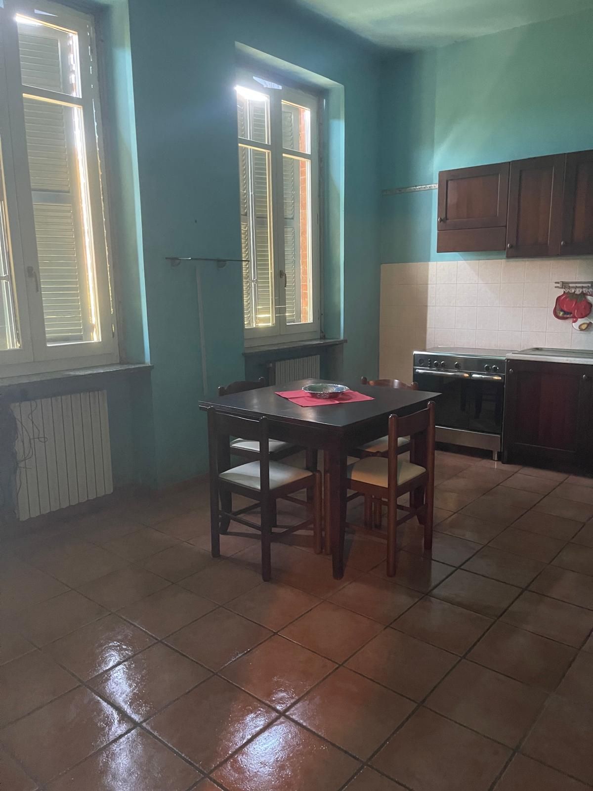 Una persona pulisce un piano di lavoro della cucina con un flacone spray e un panno blu.