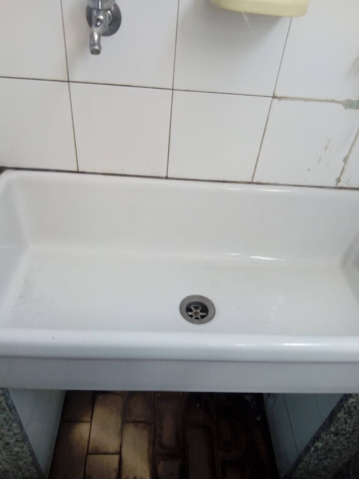 Lavabo bianco a parete con rubinetto cromato in un bagno piastrellato.