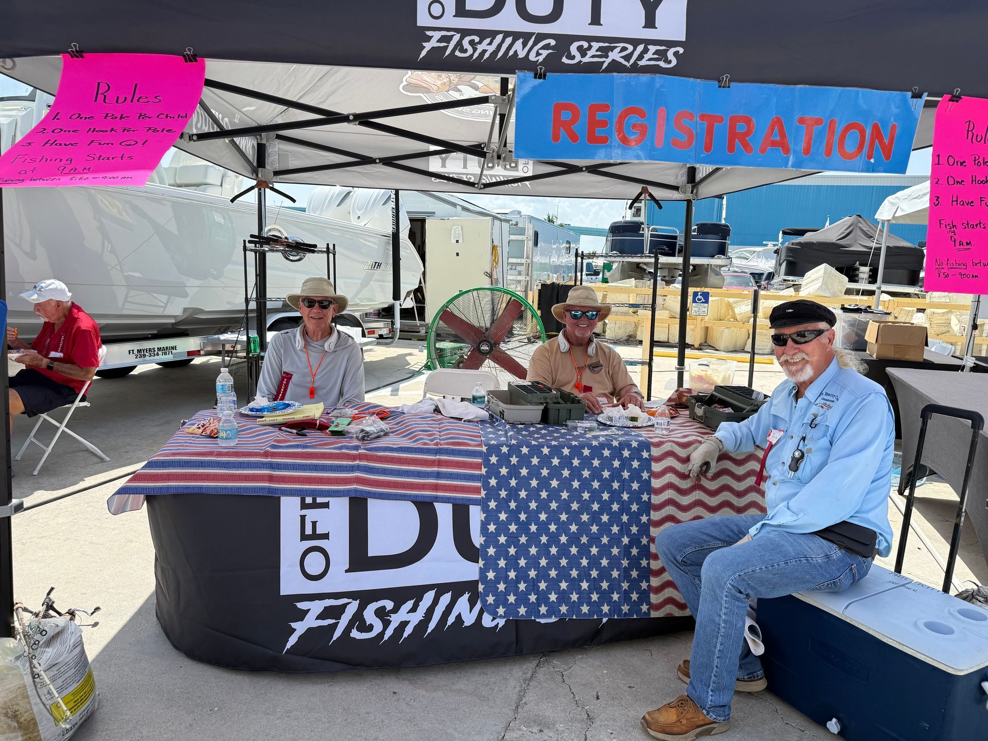 Fishing registration booth under a canopy with three volunteers seated behind a table and a blue 