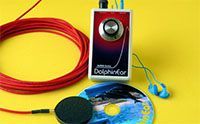 A red and silver DolphinKor device with a coiled red wire, CD, and earbuds, set on a yellow surface.