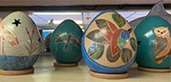 Decorated Easter eggs in muted teal, tan, and blue, lined up on a shelf