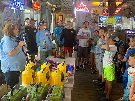 People gathered in a neon-lit arcade around yellow and green ride-on game cars.