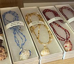 Decorative beaded necklaces in white gift boxes, in blue, gold, and red with round pendants