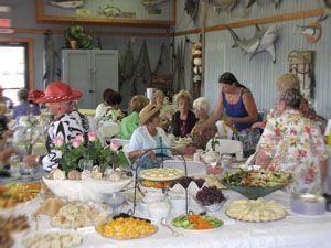 People seated at a long buffet table in a decorated dining room, serving food and chatting