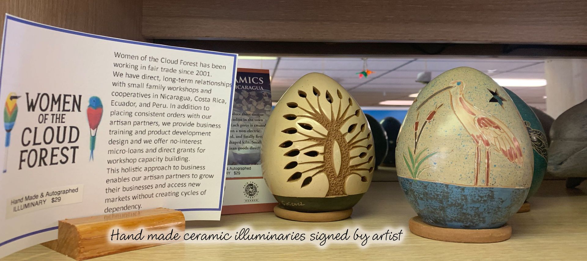 Ceramic egg-shaped art on a shelf. One egg has a tree design, another a bird. A sign reads 