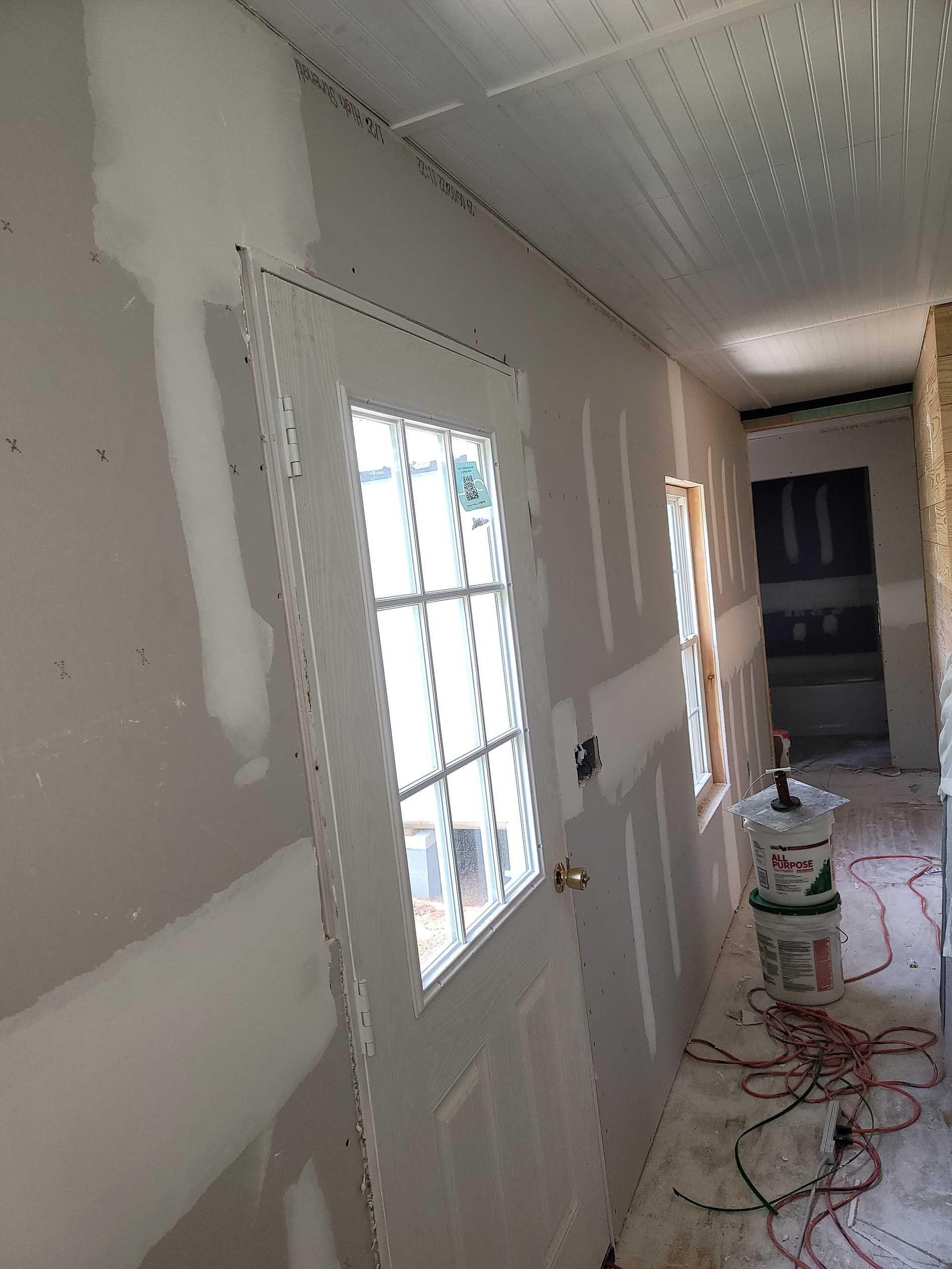 A hallway with drywall on the walls and a door.