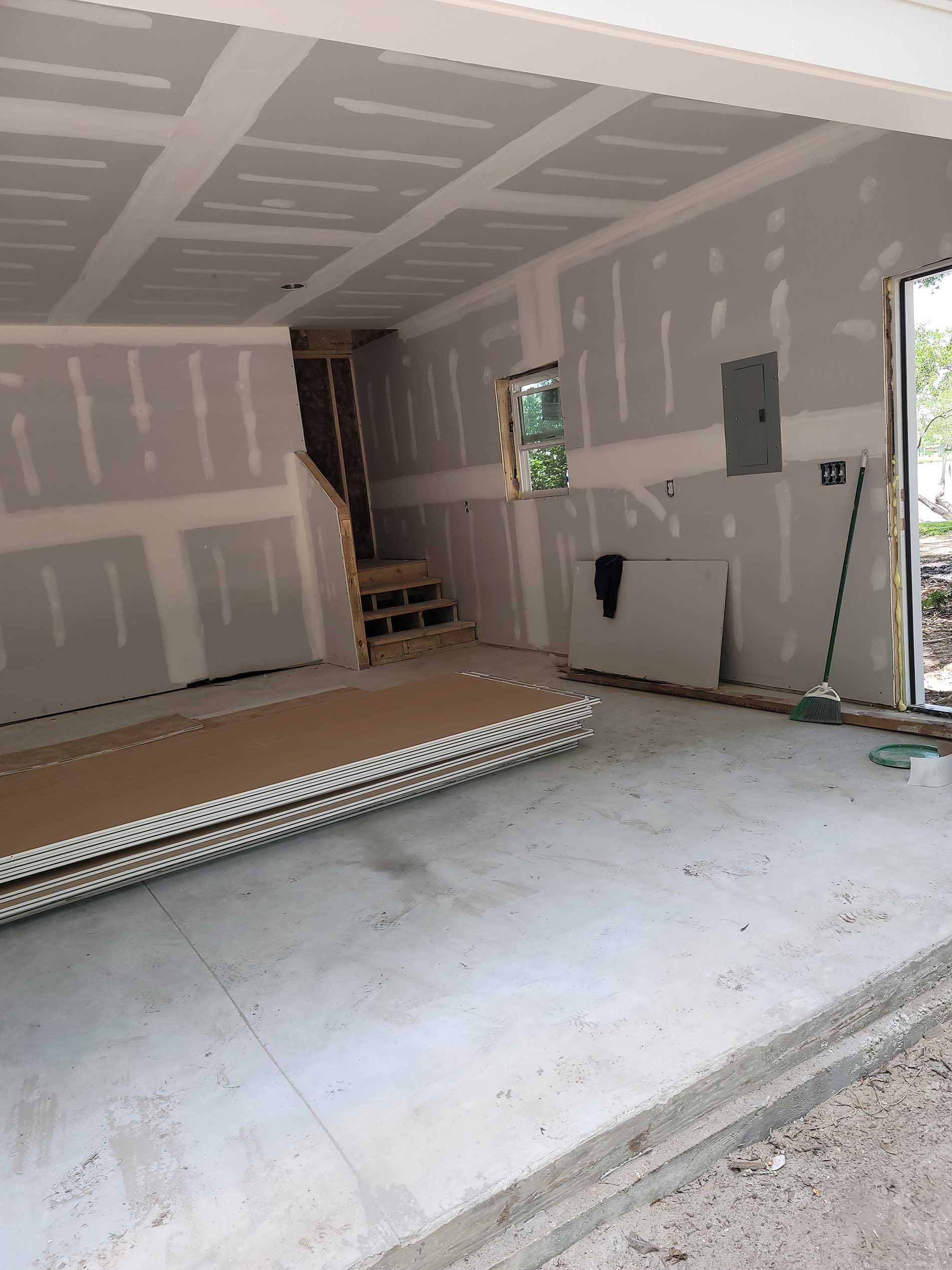 A garage under construction with a stack of drywall on the floor.