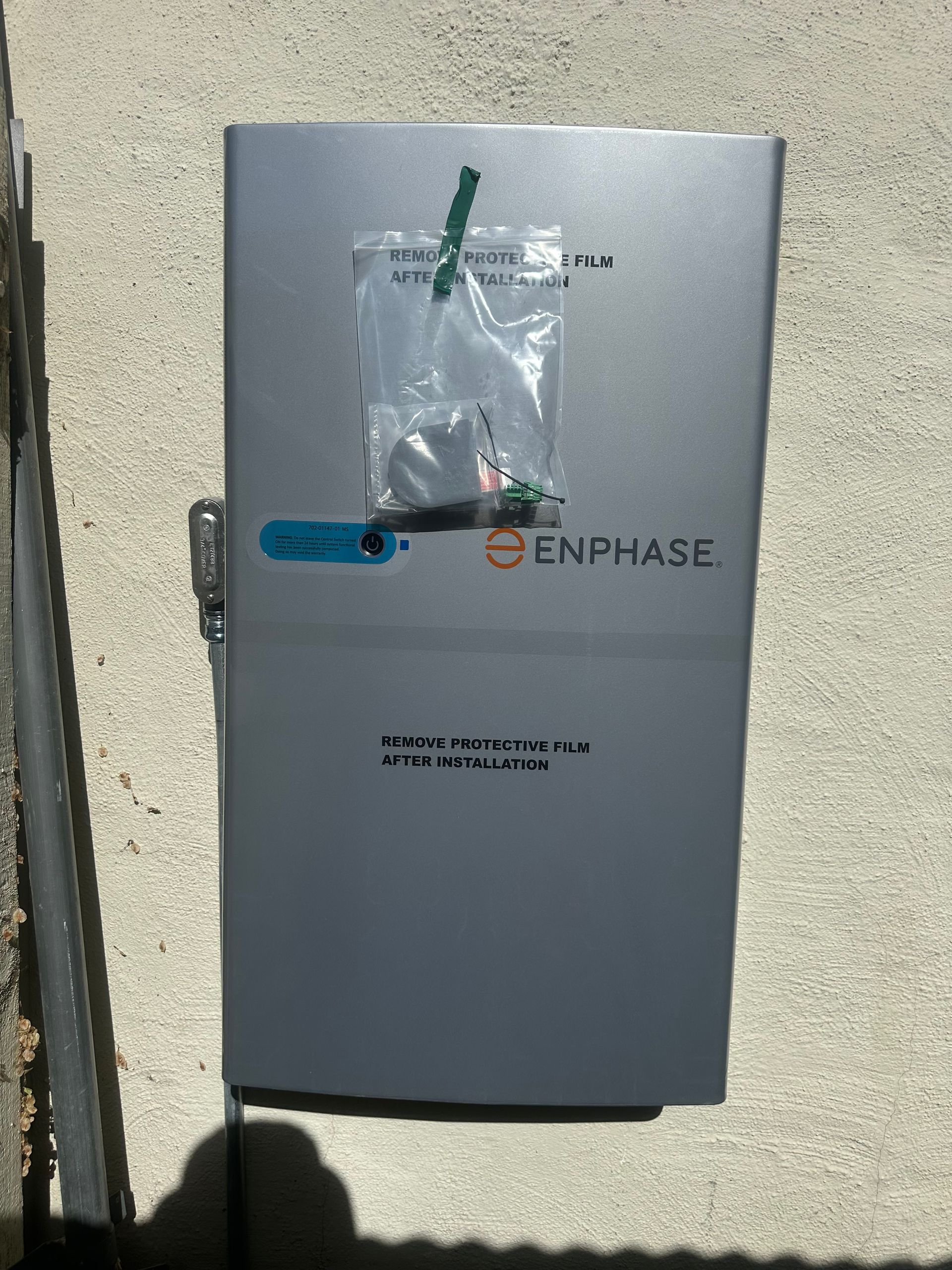 A silver enphase box is sitting on a concrete surface