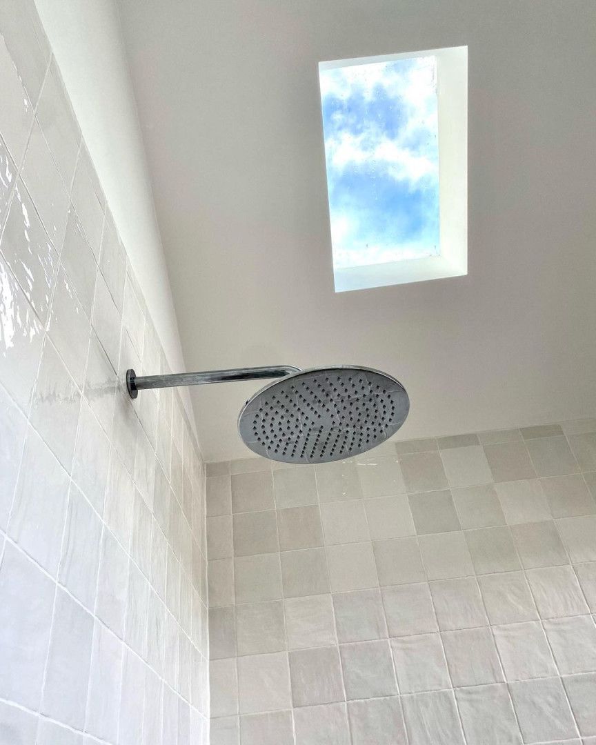 A Shower Head Is Hanging From The Ceiling In A Bathroom With A Skylight — MC Plastering In Newcastle, NSW