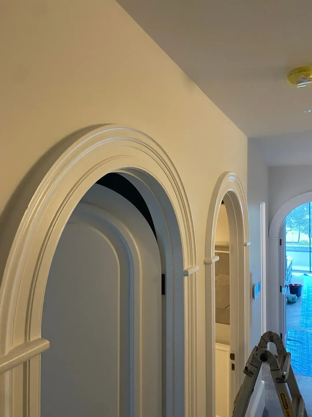 A Ladder Is Sitting In A Hallway Between Two Arched Doors — MC Plastering In Fingal Bay, NSW