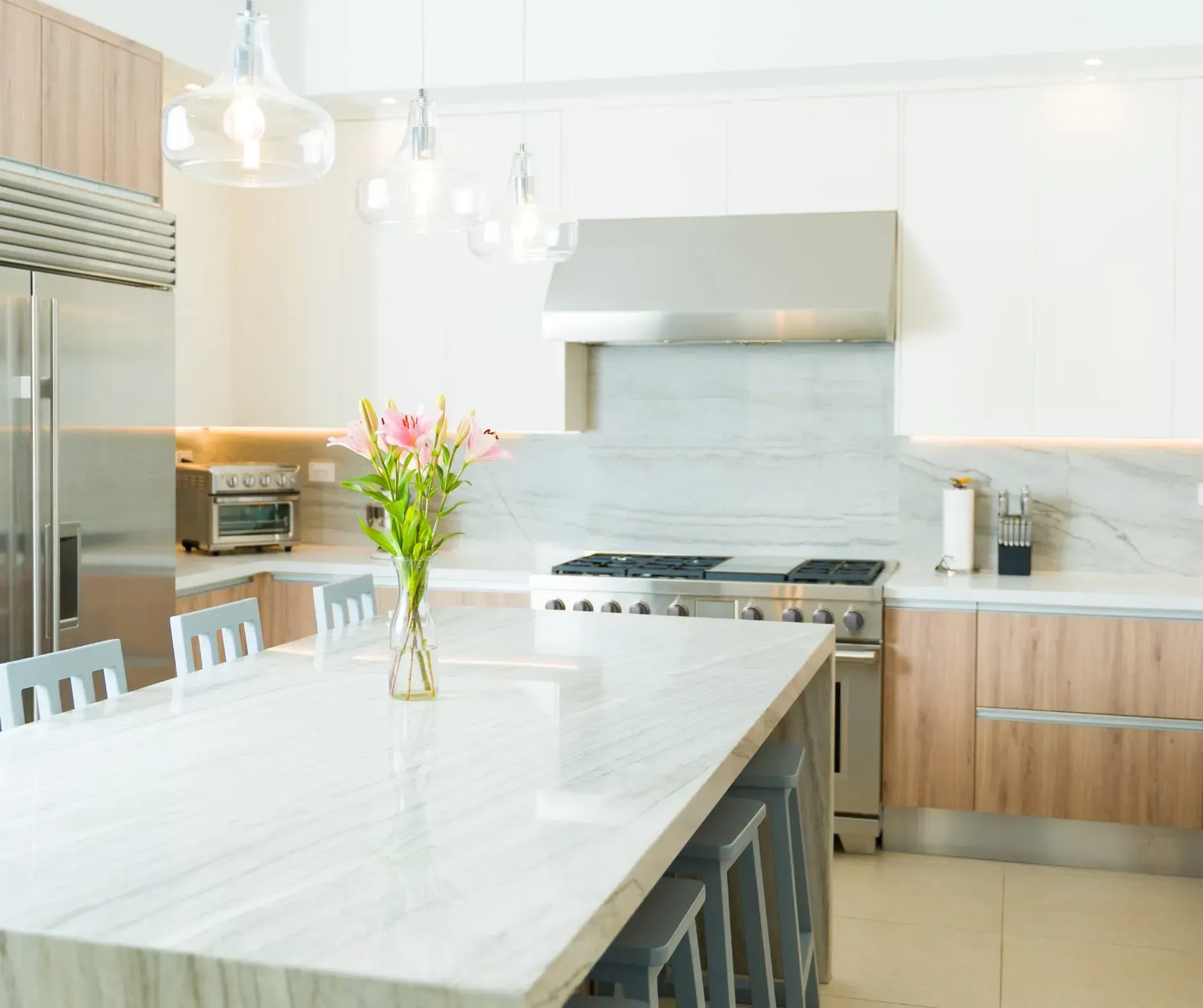 Modern kitchen with stainless steel appliances, white countertops, and wooden cabinets.