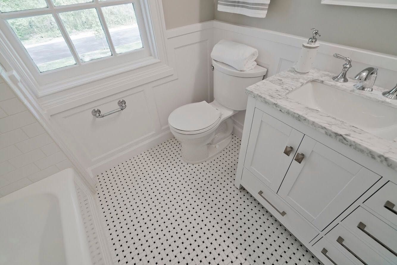 Small bright white bathroom with window, toilet, vanity sink, and black-and-white tiled floor