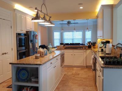 Bright white kitchen with island, granite counters, stainless appliances, and large window over the sink