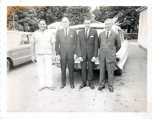 Four people standing in line in front of hearse at Mynatt Funeral Home, Inc.