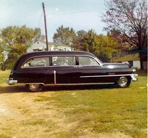 Shiny black older hearse on grass Mynatt Funeral Home, Inc.