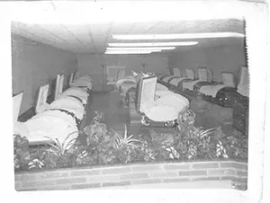 Black and white photo of casket showroom with plants in a row Mynatt Funeral Home, Inc.