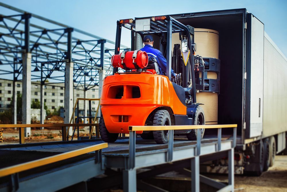 Orange Forklift Unloading a Truck at a Warehouse — Forklift Repairs & Spares In Maryborough, QLD