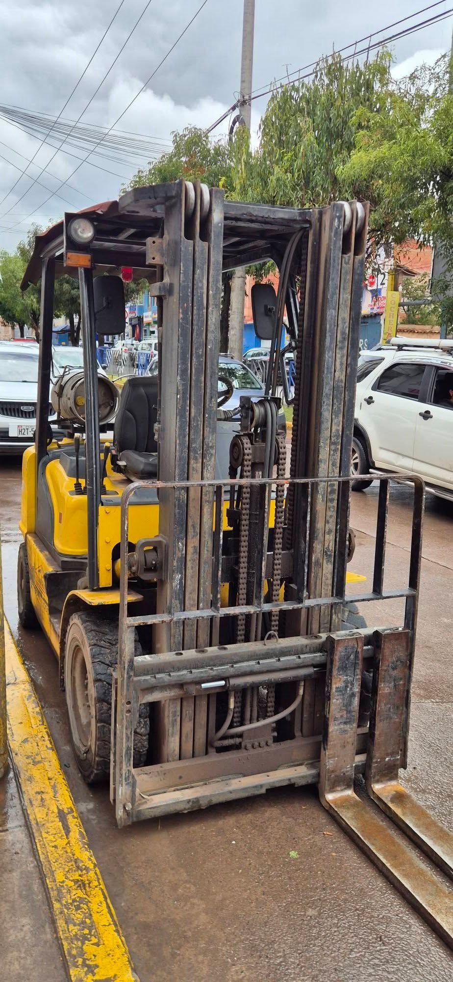 Yellow Forklift Parked On A Wet Street Beside Traffic Cones And Passing Cars — Forklift Repairs & Spares In Svensson Heights, QLD