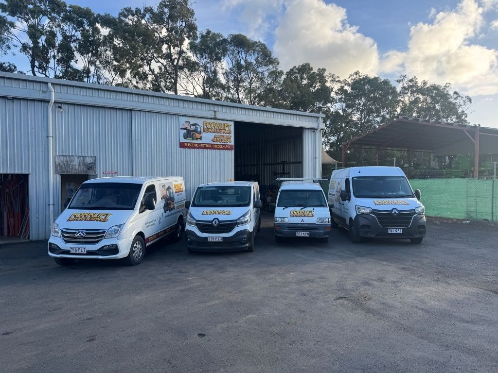 Four White Vans Parked Outside A Metal Warehouse Under A Cloudy Sky — Forklift Repairs & Spares In Svensson Heights, QLD