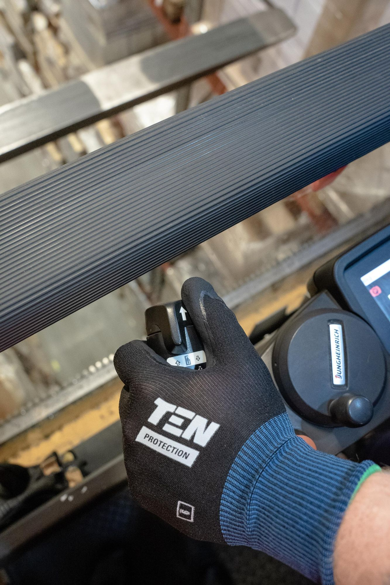 Gloved Hand Adjusting a Cable Lock on a Textured Metal Rail Outdoors — Forklift Repairs & Spares In Svensson Heights, QLD