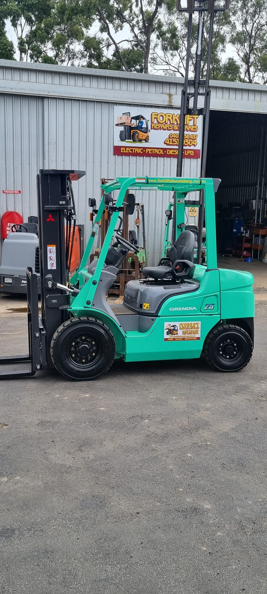 Green Forklift Parked in Front of a Warehouse — Forklift Repairs & Spares In Svensson Heights, QLD