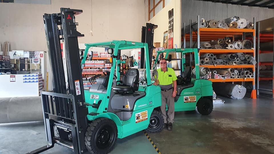 Forklift in a Warehouse With S helves and a Worker — Forklift Repairs & Spares In Svensson Heights, QLD