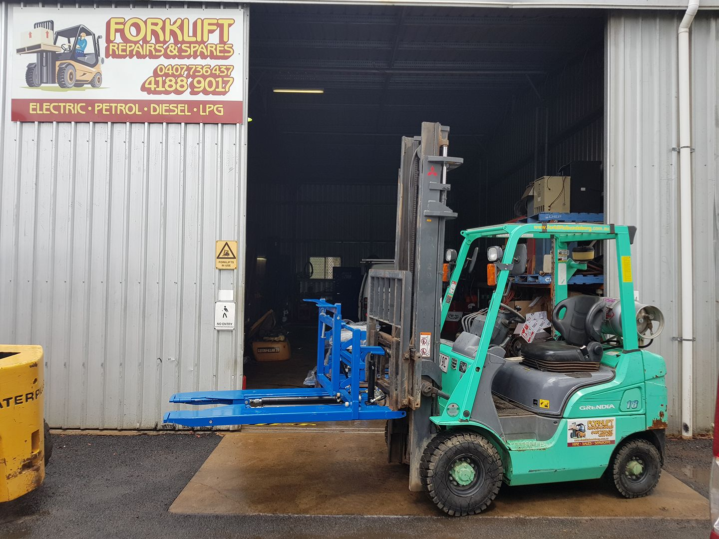 Forklift Loading Blue Machinery at a Warehouse Doorway — Forklift Repairs & Spares In Svensson Heights, QLD