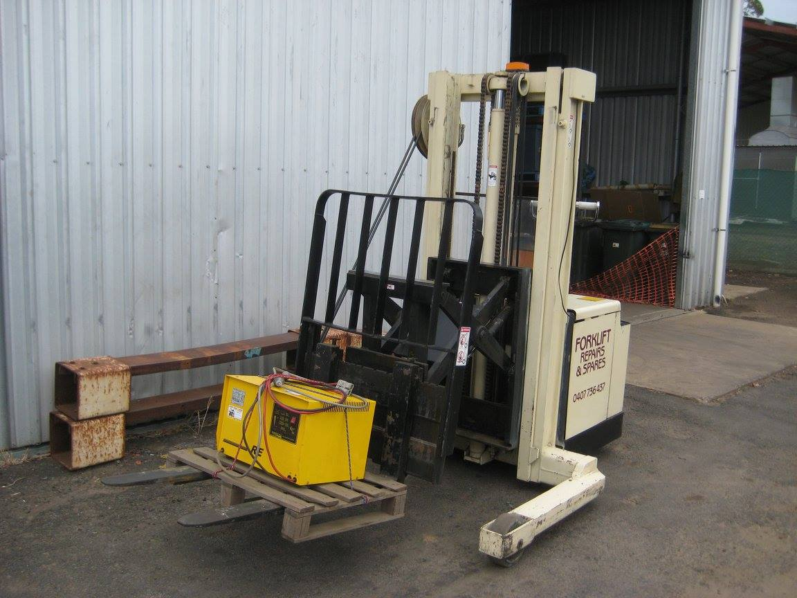 Forklift Carrying a Yellow Battery Beside a Warehouse — Forklift Repairs & Spares In Hervey Bay, QLD