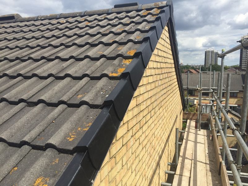 Grey tiled roof beside a yellow brick wall with scaffolding at a residential property in Oxfordshire
