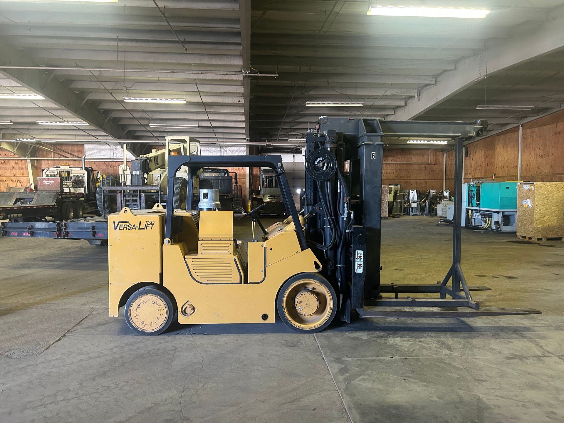 Forklift in warehouse lifting a heavy, gray block. Driver visible, wearing a mask.