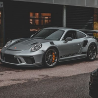 Silver Porsche 911 parked outside a building, shown in a three-quarter front view