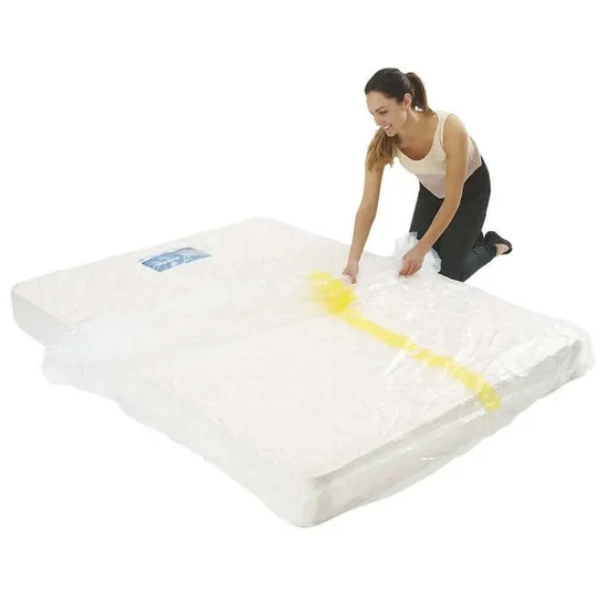 Woman kneeling on a white mattress, cleaning a yellow stain with a cloth.