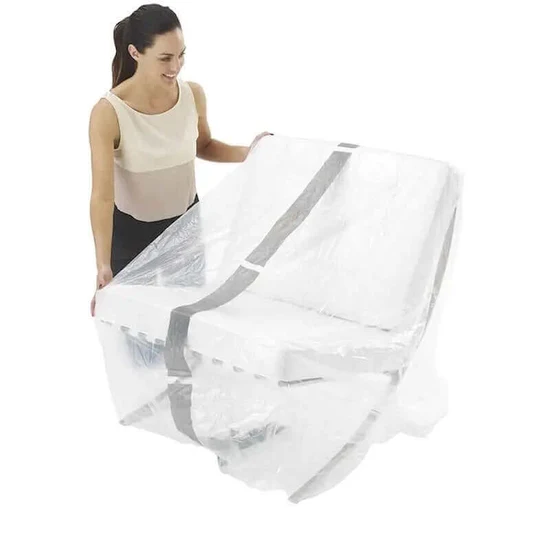 Woman unfolding a clear plastic mattress protector over a bed mattress