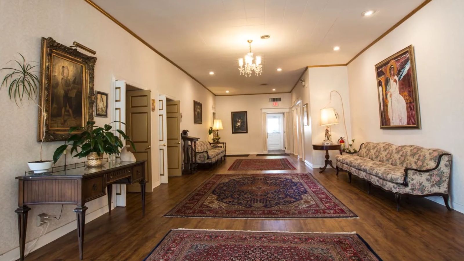 Hallway at the Caring Cremations funeral home with oriental rugs, a sofa and framed paintings