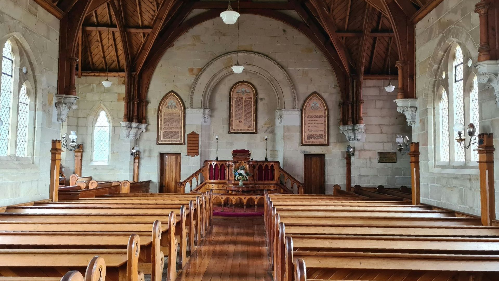Interior of a historic church with wooden pews, stone arches, and an altar at the far end