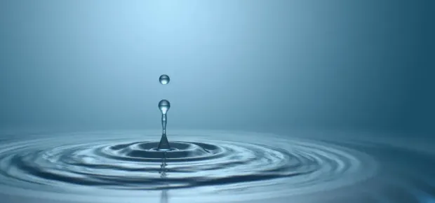 Water droplet rippling in calm water, representing water cremation (aquamation)
