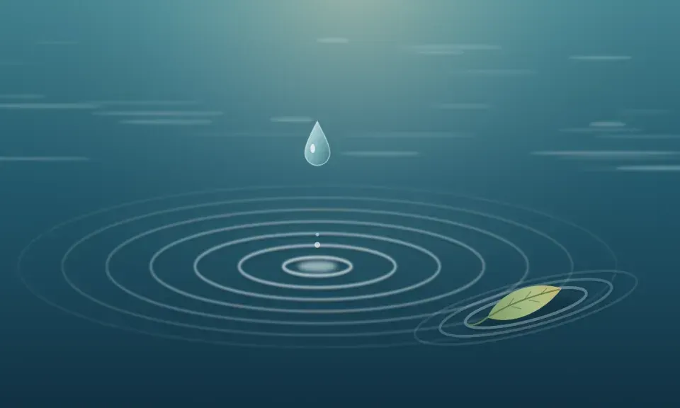 A drop of water falling into still water, with gentle ripples and a floating leaf