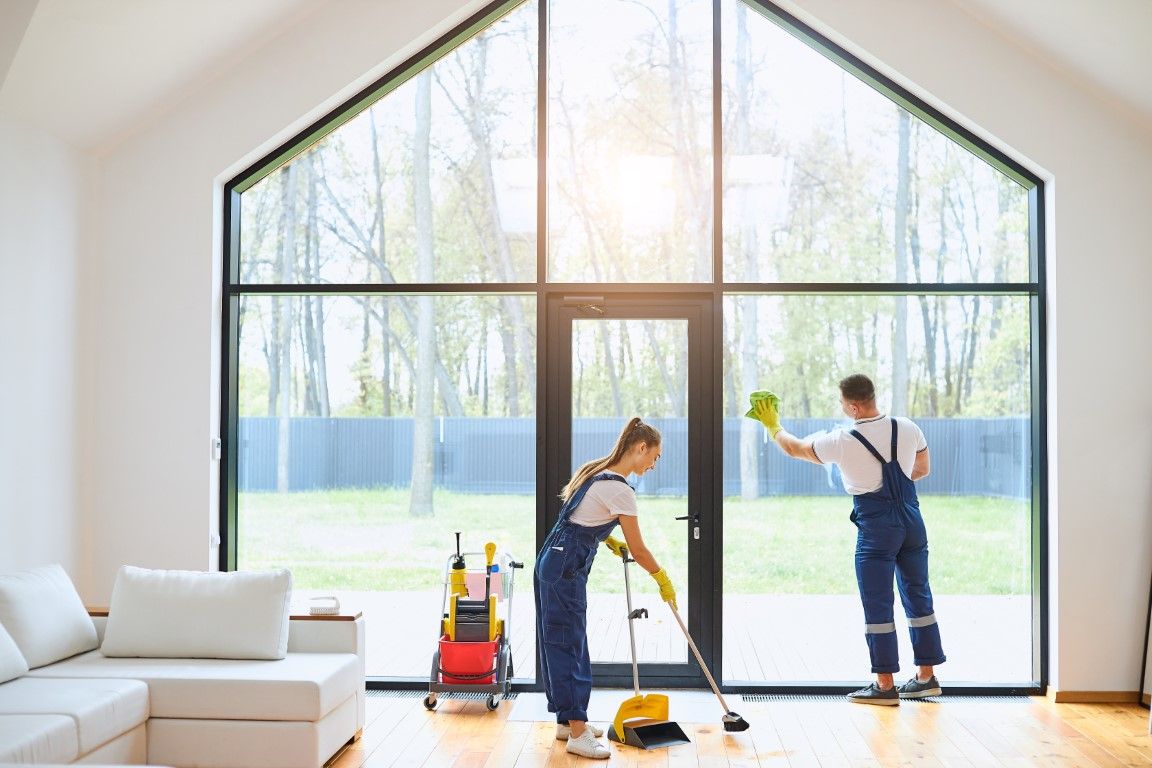 A man and a woman are cleaning a living room.