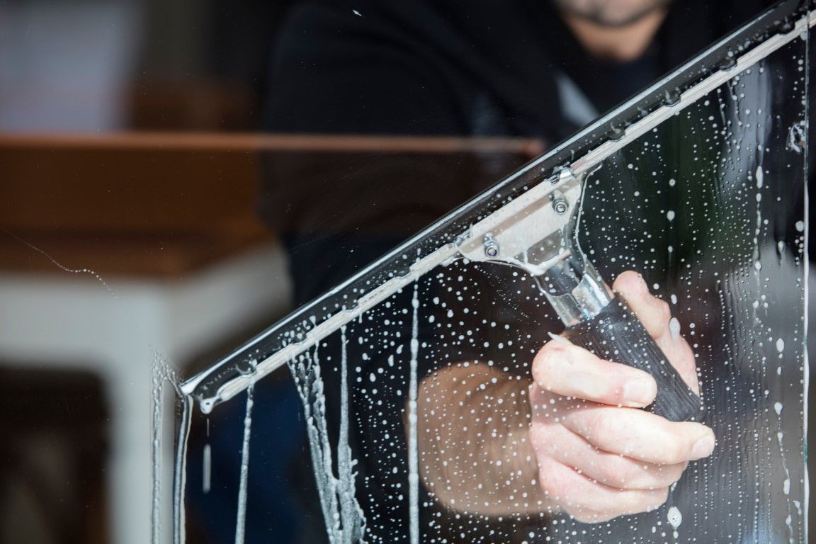 A man is cleaning a window with a squeegee.