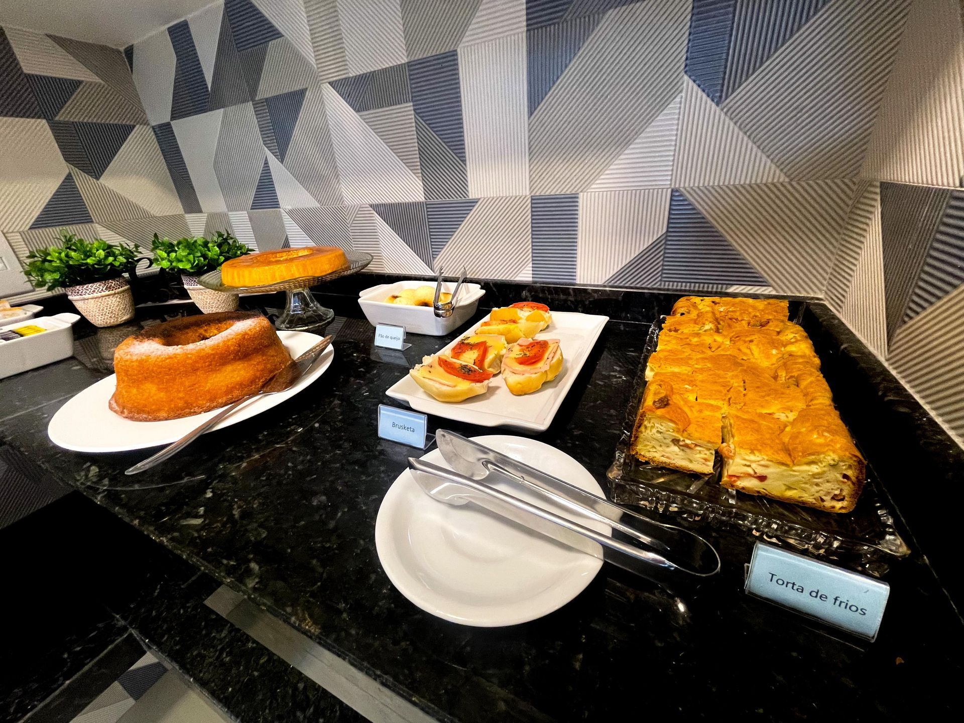 Um balcão de buffet com uma variedade de bolos e salgados, incluindo um bolo Bundt redondo e fatias de torta.