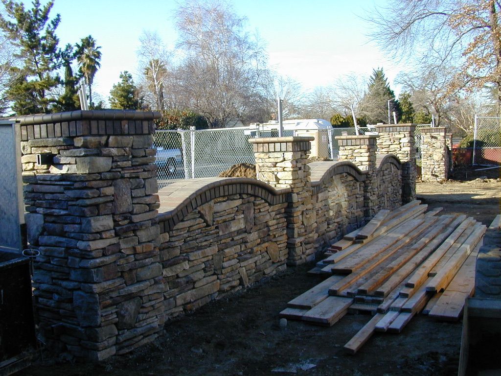 A stone wall with a pile of wood in front of it