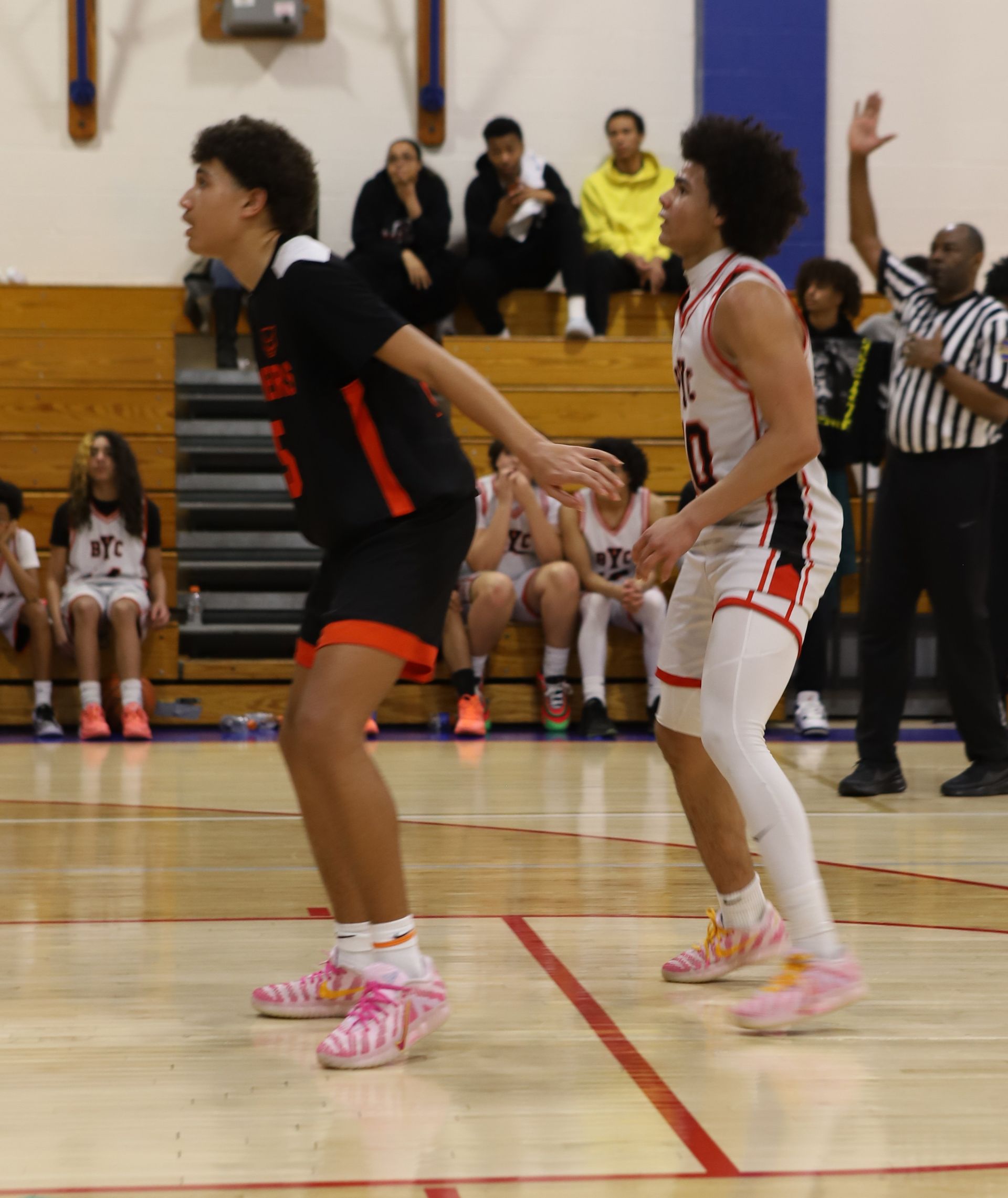 Two basketball players in black and white uniforms compete on an indoor court.
